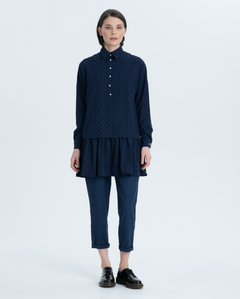 Elongated blouse with a wide flounce at the bottom of the product. A turn-down collar, a thin graphic print on a dark blue background, cuffs and placket with original voluminous buttons on the leg give it a special chic.