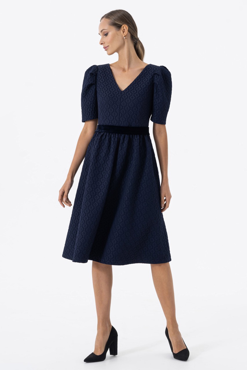 Evening dress from jacquard with a geometric texture with a fastener — a metal zipper on the back. Cut-off dress at the waist with a full skirt at the gathering and voluminous sleeves with pintucks. A velvet belt is attached to the dress.