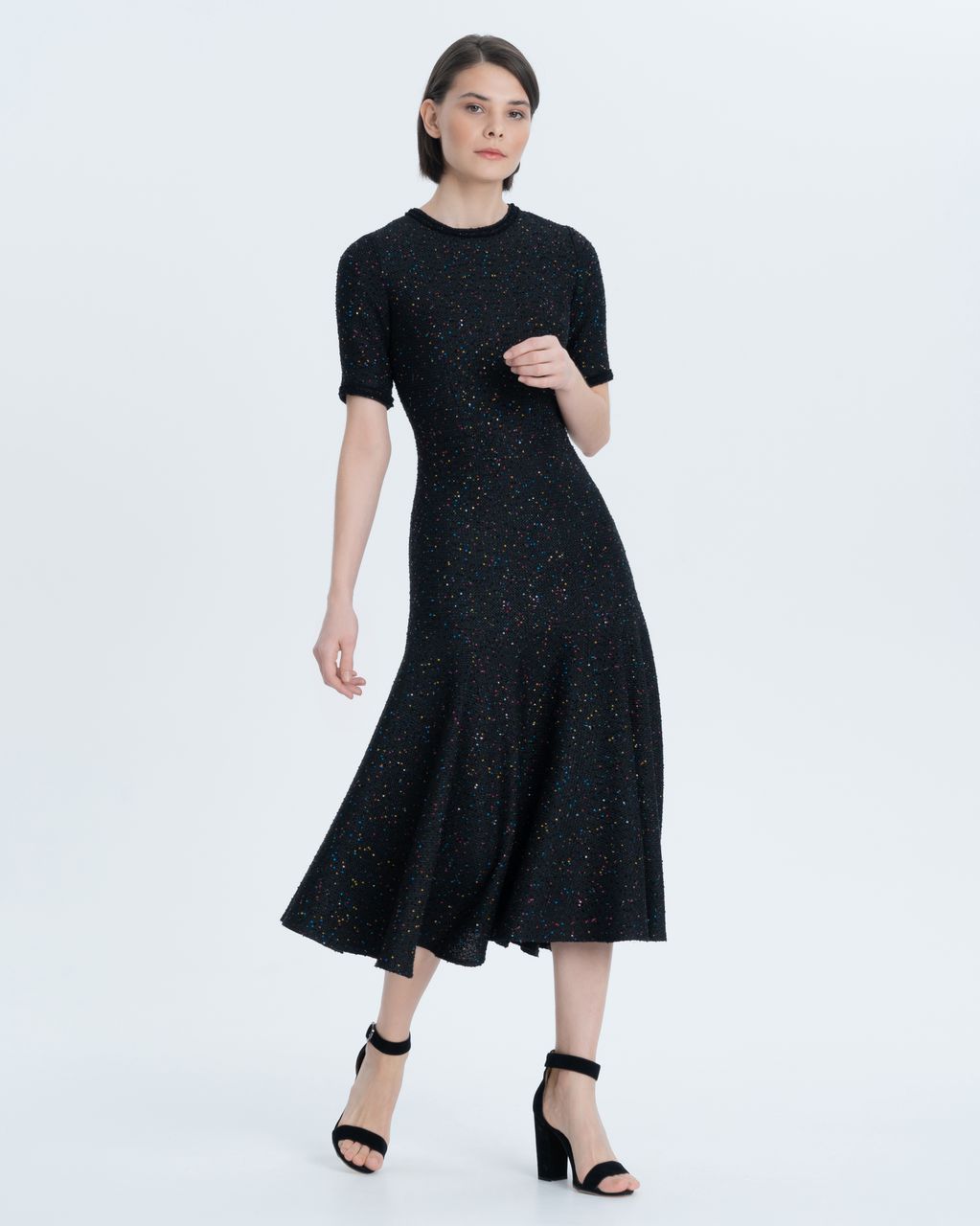Dress of the adjacent silhouette with a wide cut-off Valan. It is made of black textured tweed, embroidered with small colored sequins. A neat round neck and a V-neck sleeve to the elbow are trimmed with black braid. Metal zip closure on the back.