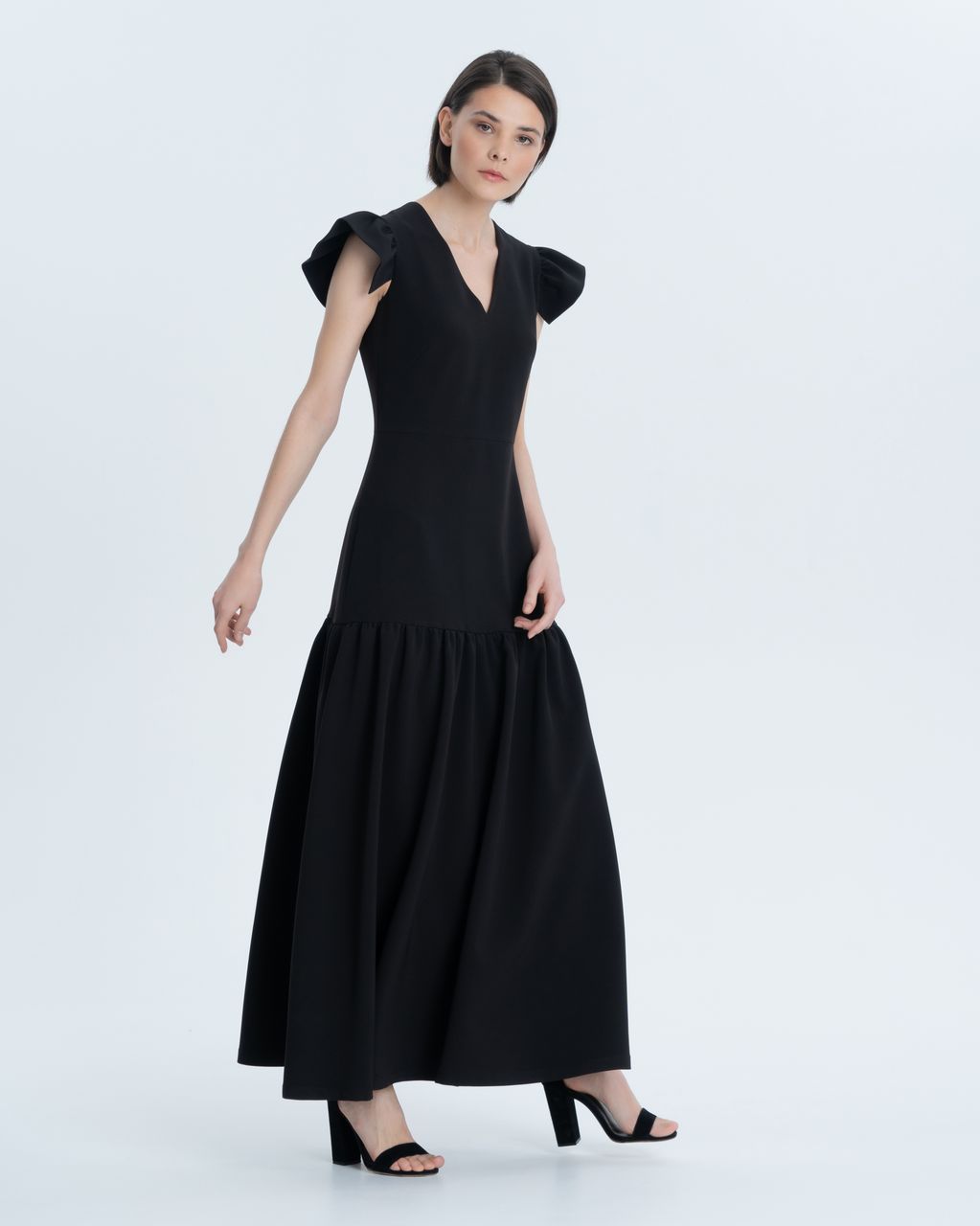 Evening dress made of thick crepe with geometric wing sleeves. An exquisite minimalistic silhouette, a longitudinal cutout and a cut-off flowing flounce make it versatile for any occasion and type of figure.