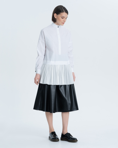 Elongated white blouse with a wide flounce at the bottom of the product. The stand-up collar, cuffs and placket with original voluminous buttons on the leg give it a special chic.