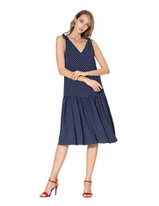 Double crepe dress in blue with a pattern of white small peas. On the shoulders are adjustable tie straps and below the waist line a detachable wide shuttlecock.